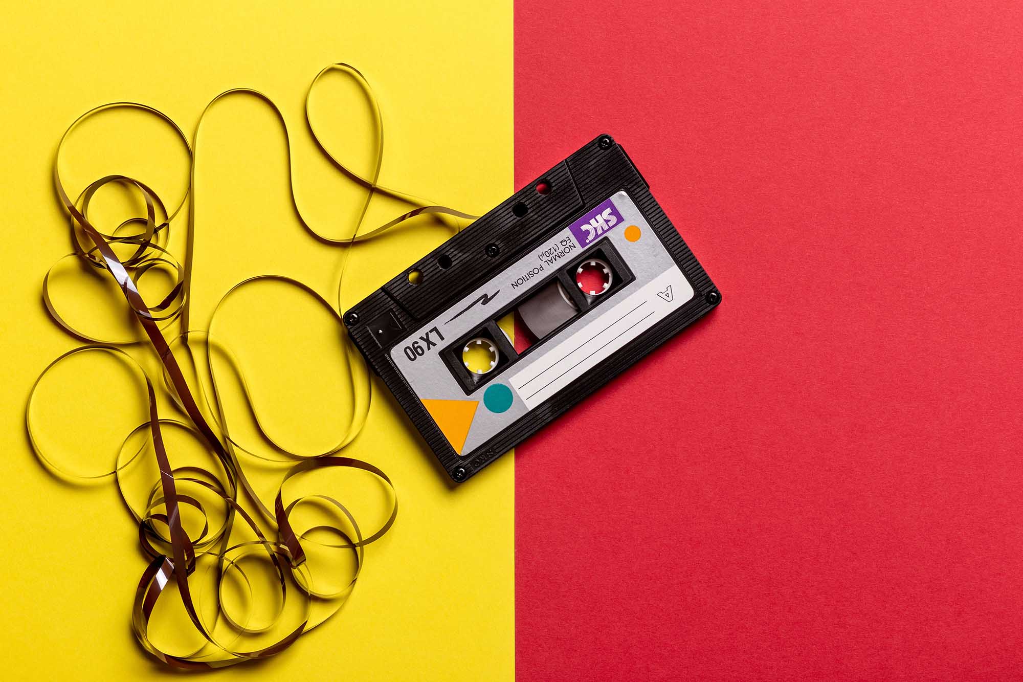 A cassette with its tape unwound on a bright two-tone background. Mixtape
