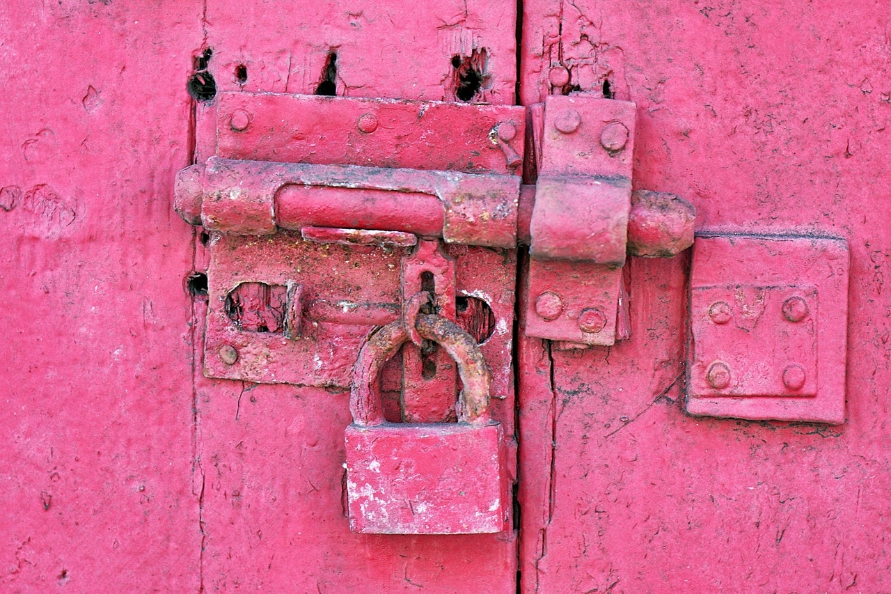 An old door and lock, crusted in thick pink paint. Lock